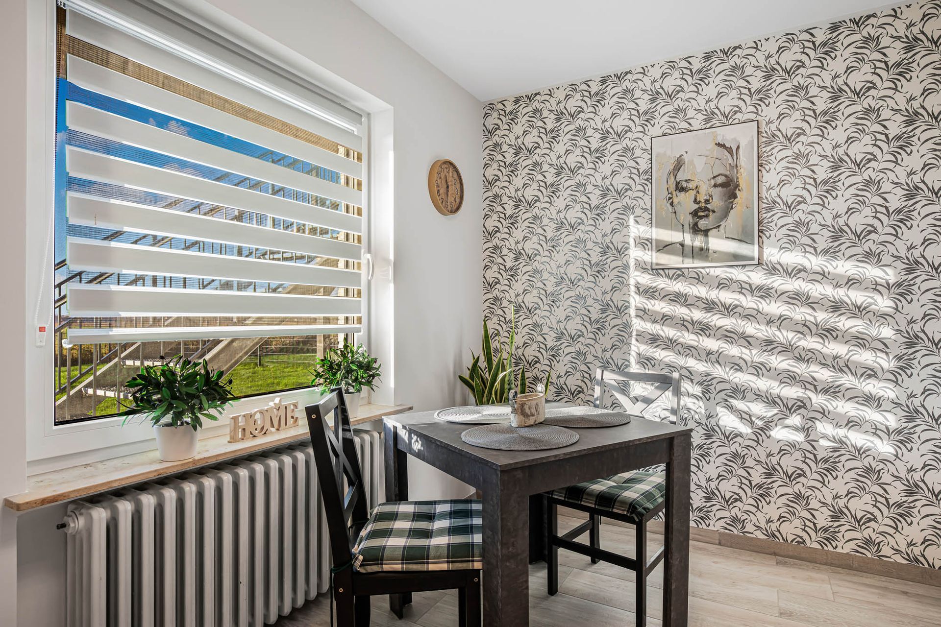 Ein Esszimmer mit Tisch und Stühlen und einem Fenster mit Jalousien.