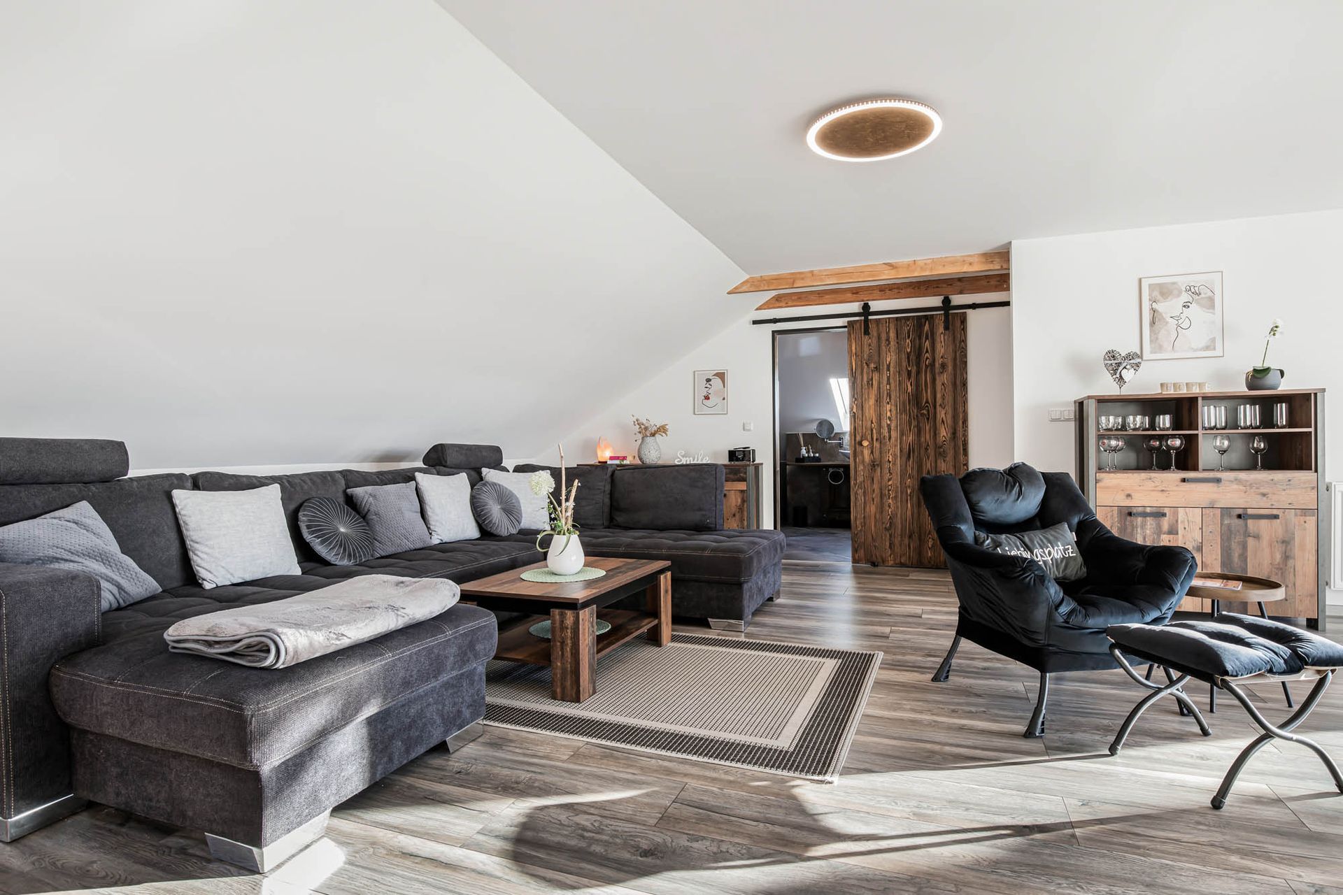 Ein Wohnzimmer mit Couch, Sessel, Tisch und Teppich.