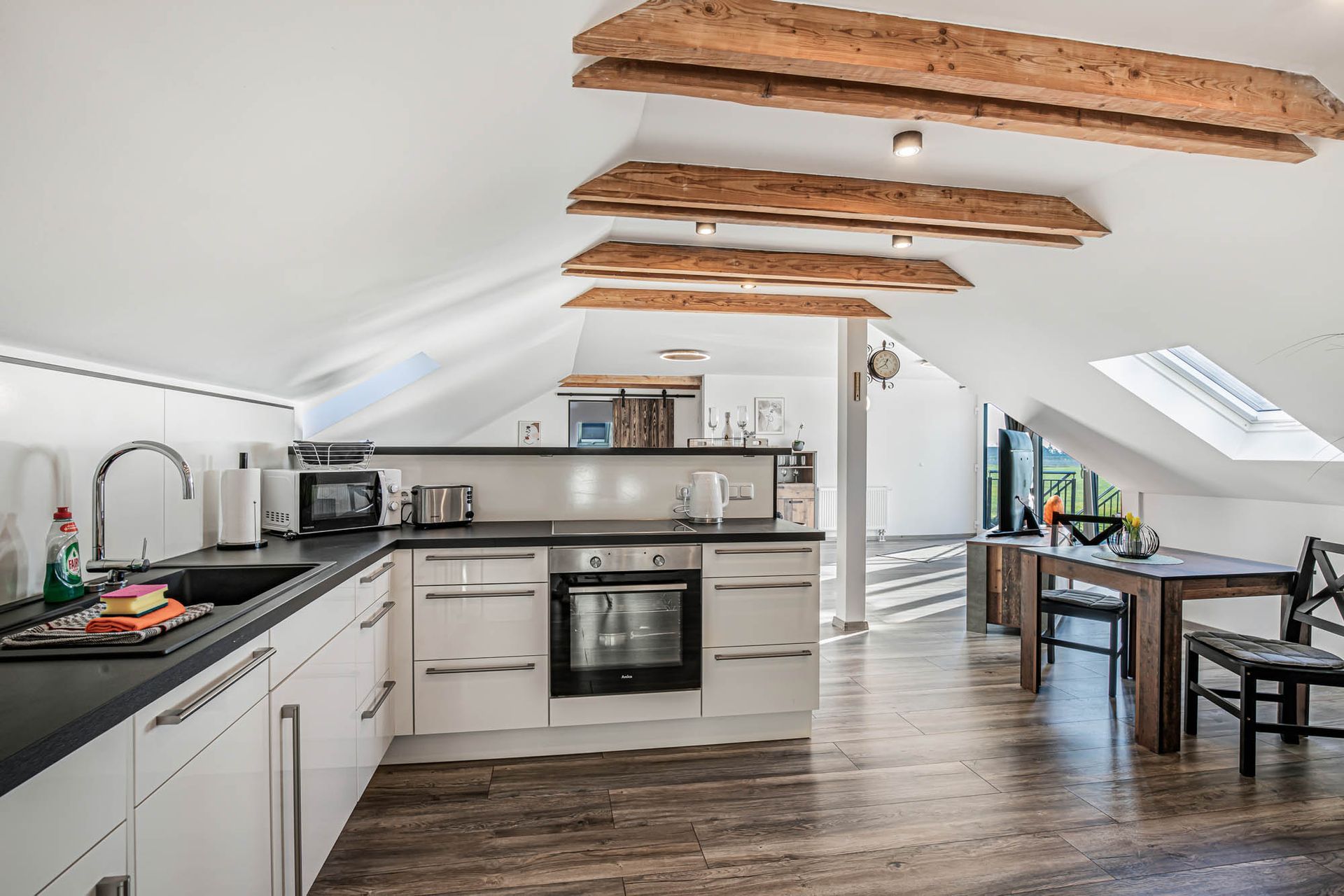 Eine Küche mit weißen Schränken und Holzböden und einem Tisch und Stühlen.