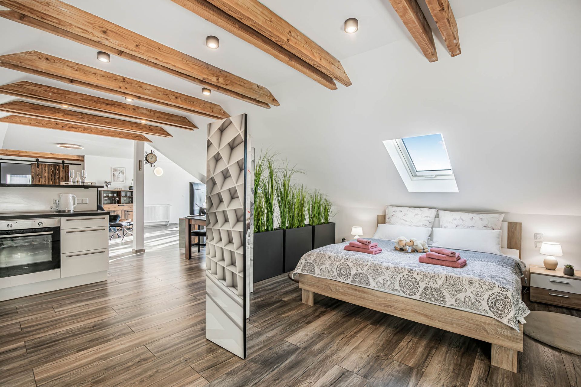 Ein Schlafzimmer mit Kingsize-Bett und einer Küche im Hintergrund.