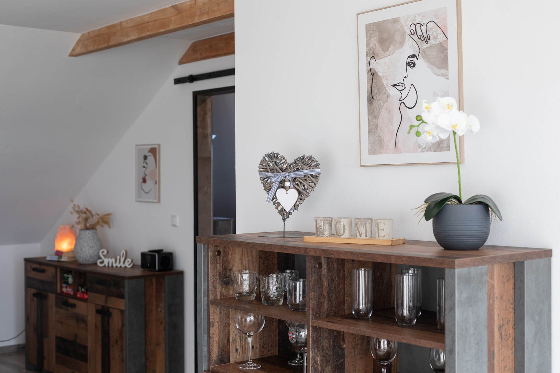 Ein Wohnzimmer mit einem Holzregal voller Weingläser und einem Bild an der Wand.