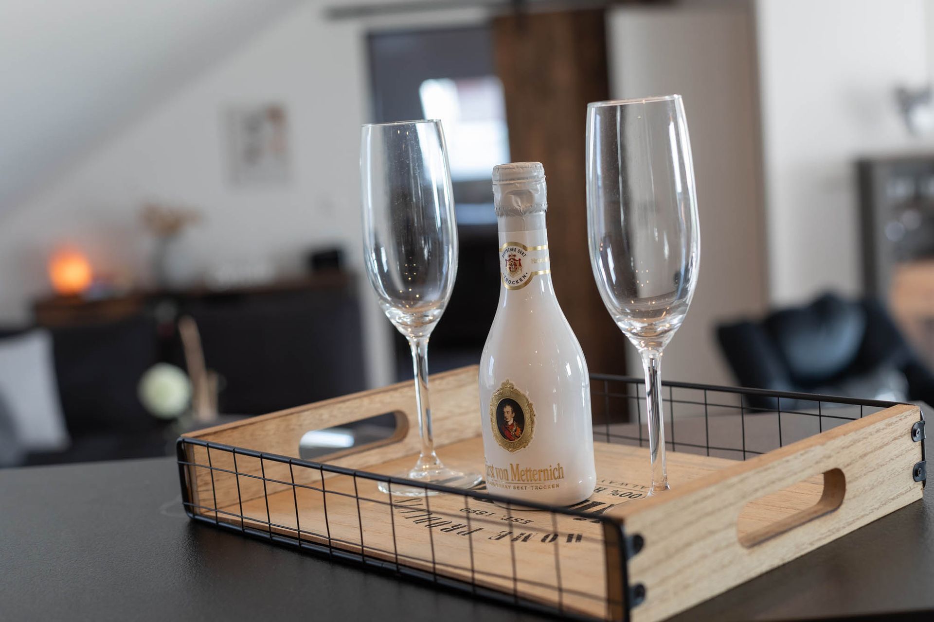 Ein Holztablett mit zwei Champagnergläsern und einer Flasche Wein darauf.