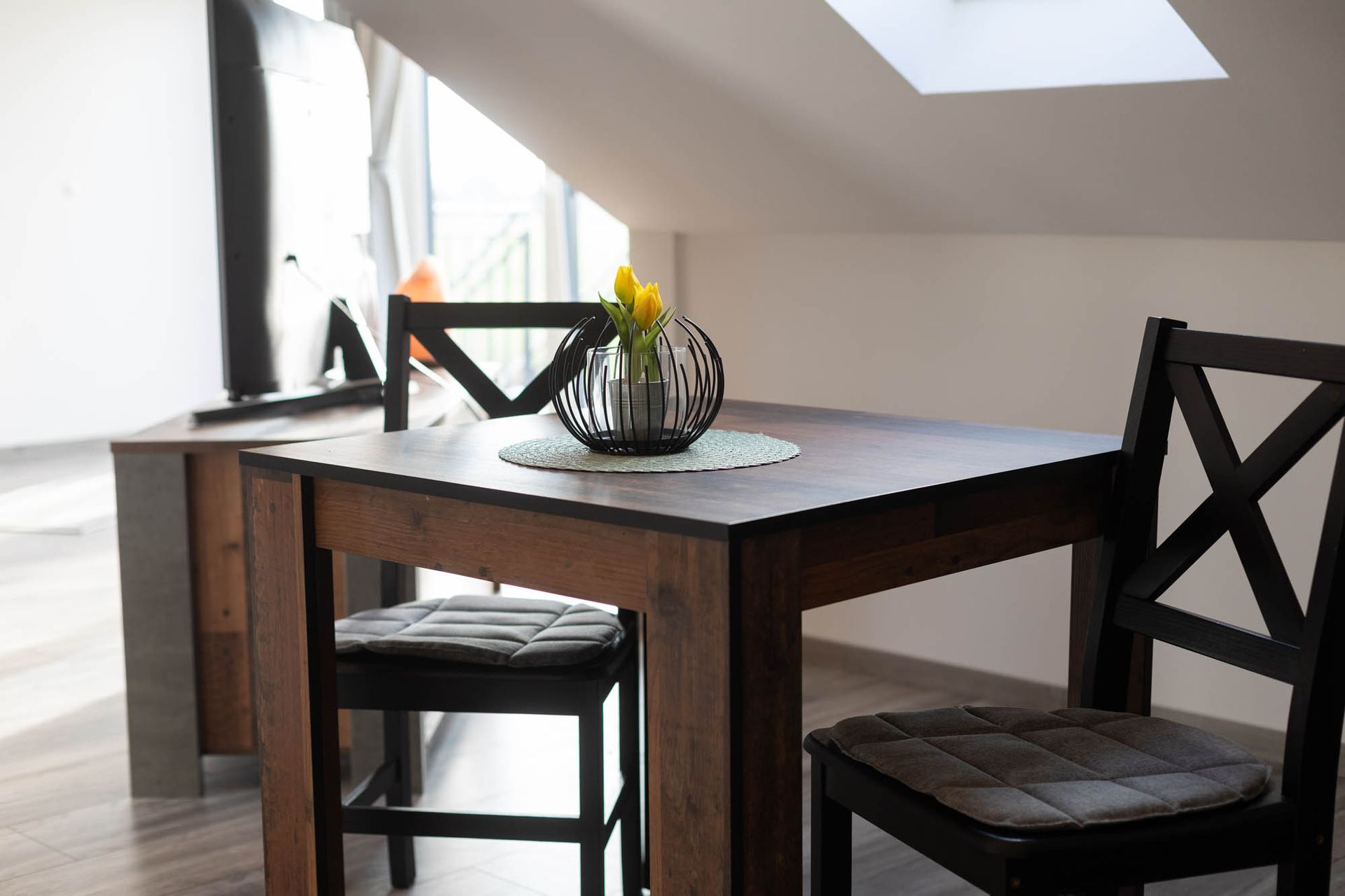 Ein Tisch mit zwei Stühlen und einer Vase mit Blumen darauf