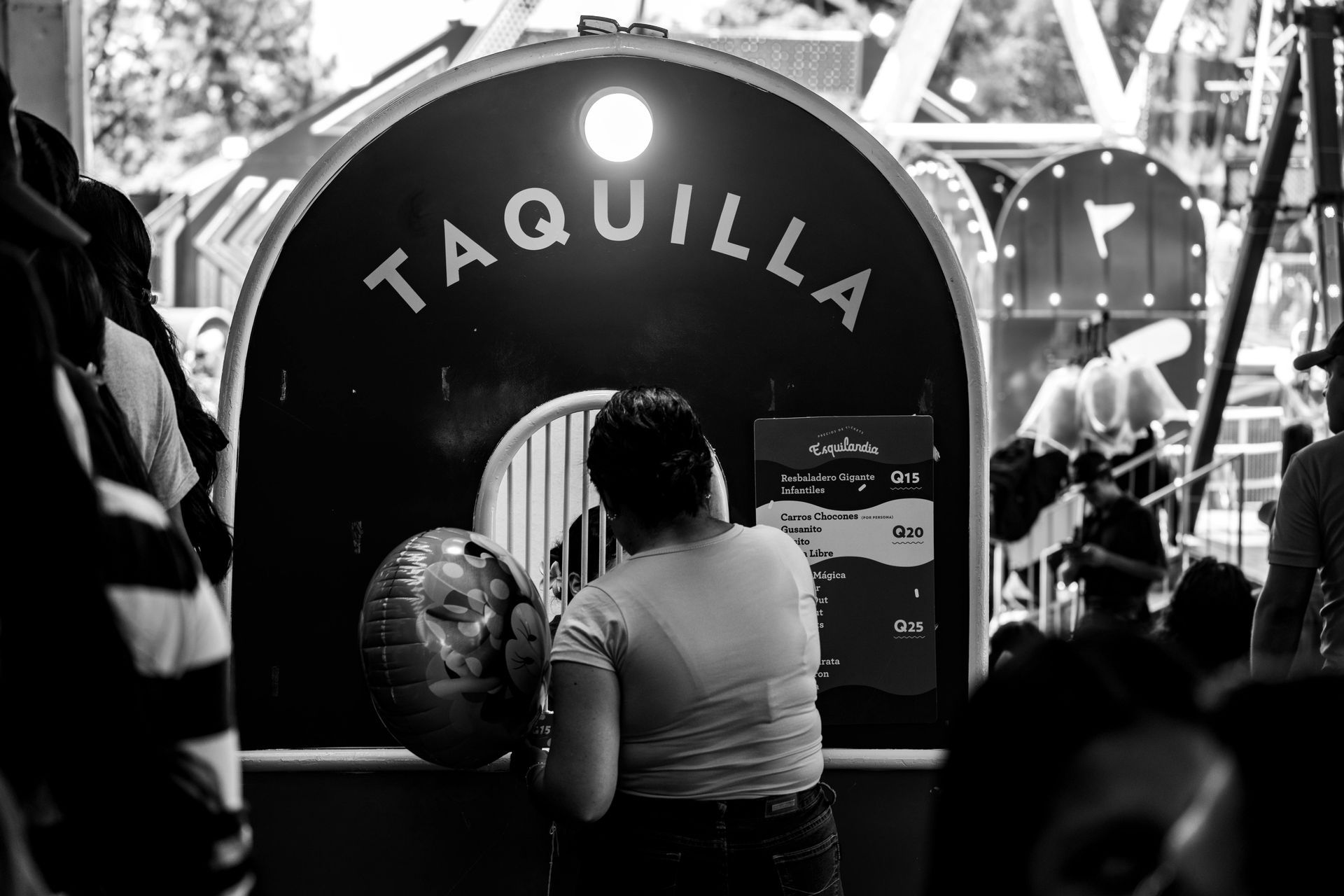 Mujer en una taquilla que parece un tren; “TAQUILLA” está encima de la ventana.