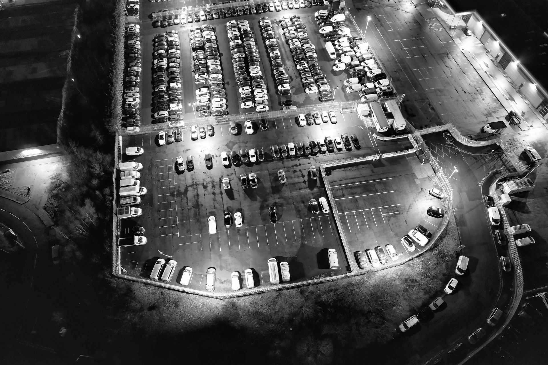 Vista aérea de un estacionamiento bien iluminado lleno de automóviles por la noche.