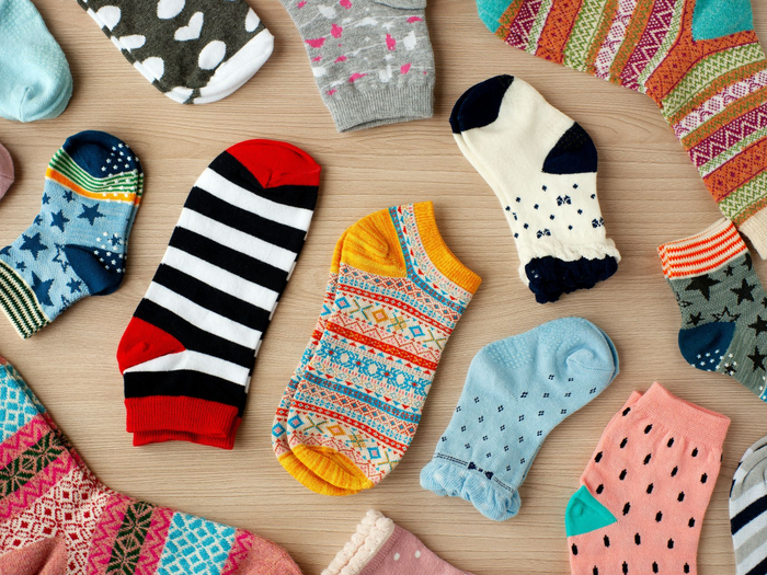 Chaussettes colorées à motifs, à rayures, à pois et à motifs ludiques, disposées sur une surface en bois.