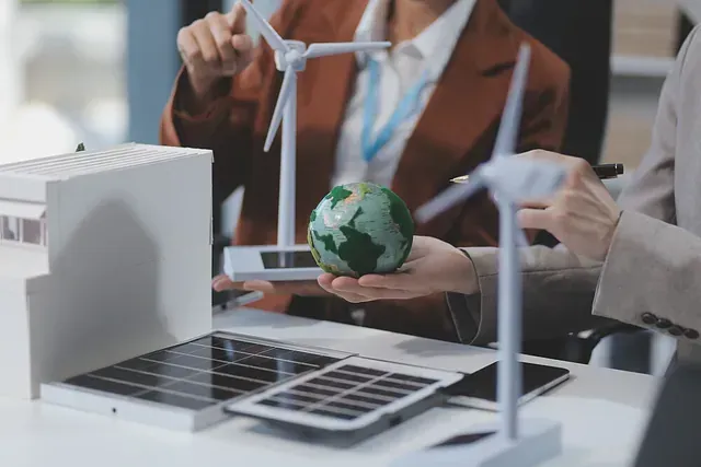 Una mujer sostiene un globo terráqueo frente a una computadora portátil y molinos de viento.