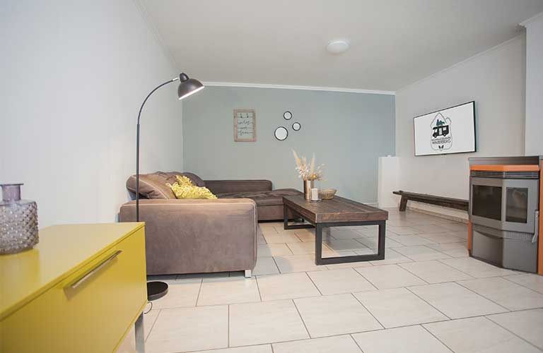 Ein Wohnzimmer mit Couch, Tisch, Lampe und Ofen.