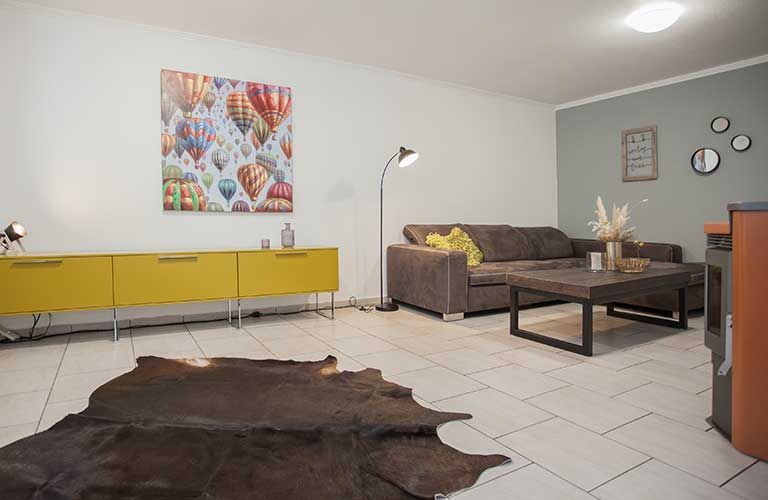 Ein Wohnzimmer mit Couch, Couchtisch und Kuhfellteppich.