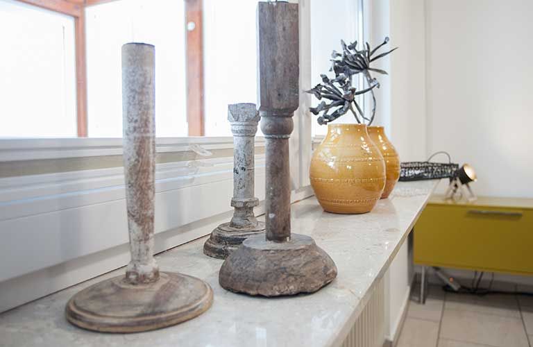 Drei Kerzenständer stehen neben einer Blumenvase auf einem Fensterbrett.