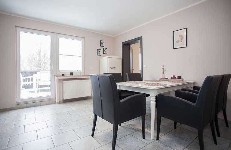 Ein Esszimmer mit Tisch und Stühlen und einem großen Fenster.