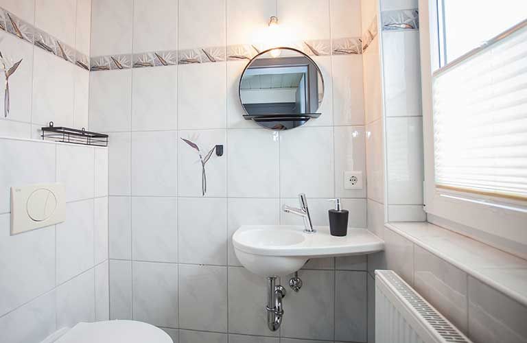 Ein Badezimmer mit Toilette, Waschbecken und Spiegel