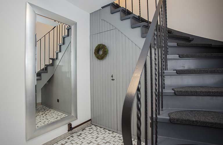 Ein Flur mit einer Treppe und einem großen Spiegel.