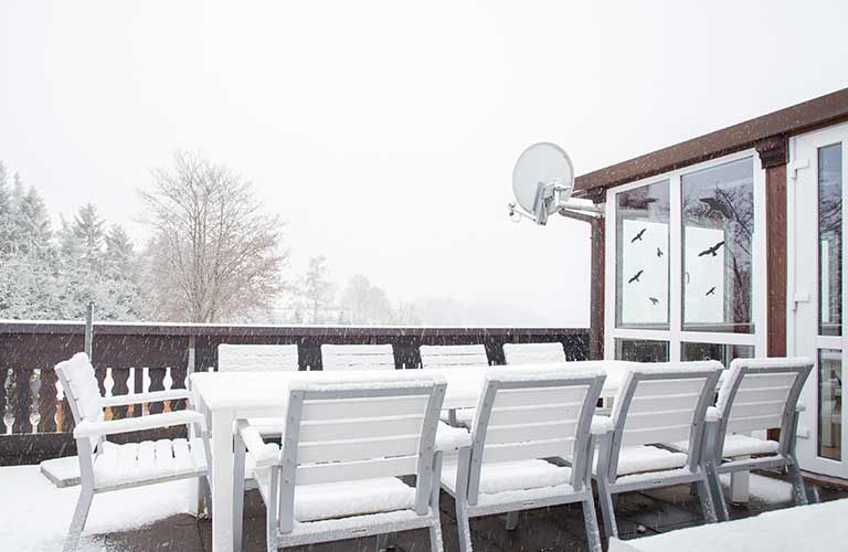 Eine Terrasse mit einem Tisch und Stühlen, die mit Schnee bedeckt sind.