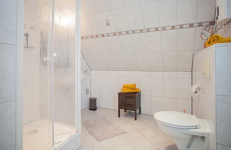 Ein Badezimmer mit Toilette, Dusche und gelben Handtüchern.