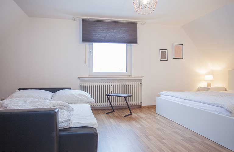 Ein Schlafzimmer mit zwei Betten, einer Couch, einem Tisch und einem Fenster.