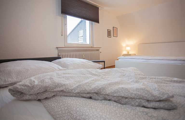 Ein Schlafzimmer mit zwei Betten und einem Fenster mit Jalousien.