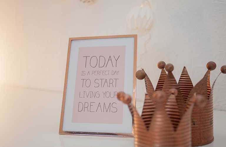 Neben einem Poster mit der Aufschrift „Heute ist der perfekte Tag, um anzufangen, Ihre Träume zu leben“ steht eine Krone.