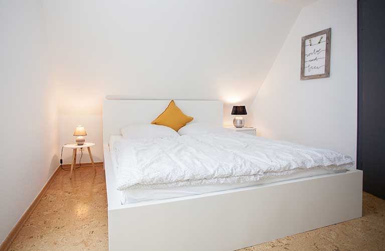 Ein Schlafzimmer mit einem weißen Bett und einem gelben Kissen.