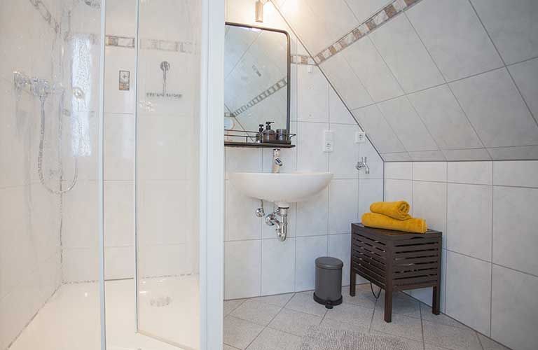 Ein Badezimmer mit Waschbecken und ebenerdiger Dusche.