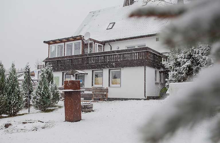 Ein großes weißes Haus mit Balkon ist mit Schnee bedeckt.