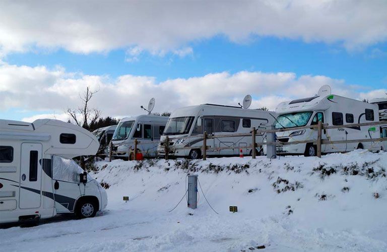 Eine Reihe Wohnmobile ist im Schnee geparkt.