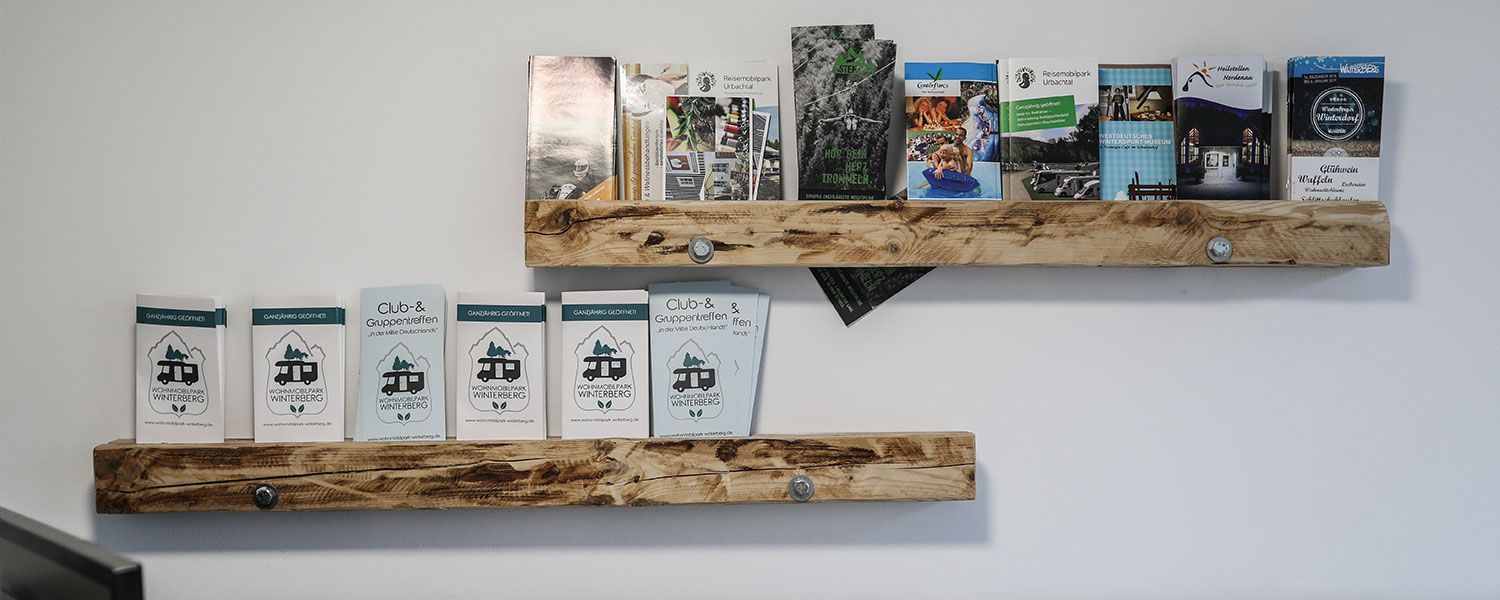 Zwei Holzregale voller Bücher an einer weißen Wand.