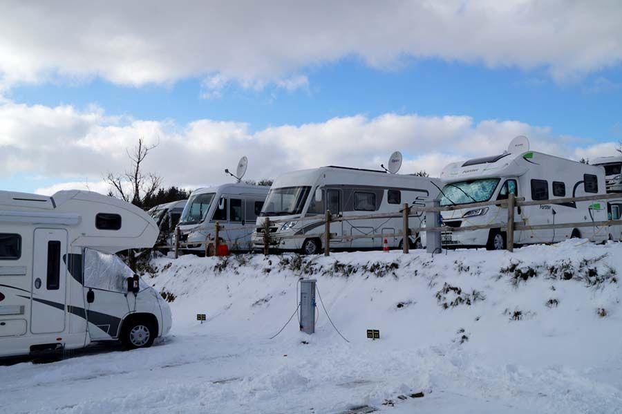 Eine Reihe Wohnmobile ist im Schnee geparkt.