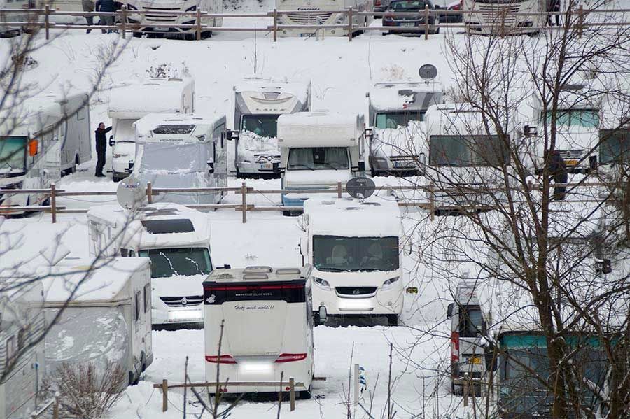 Eine Menge Wohnmobile sind im Schnee geparkt.