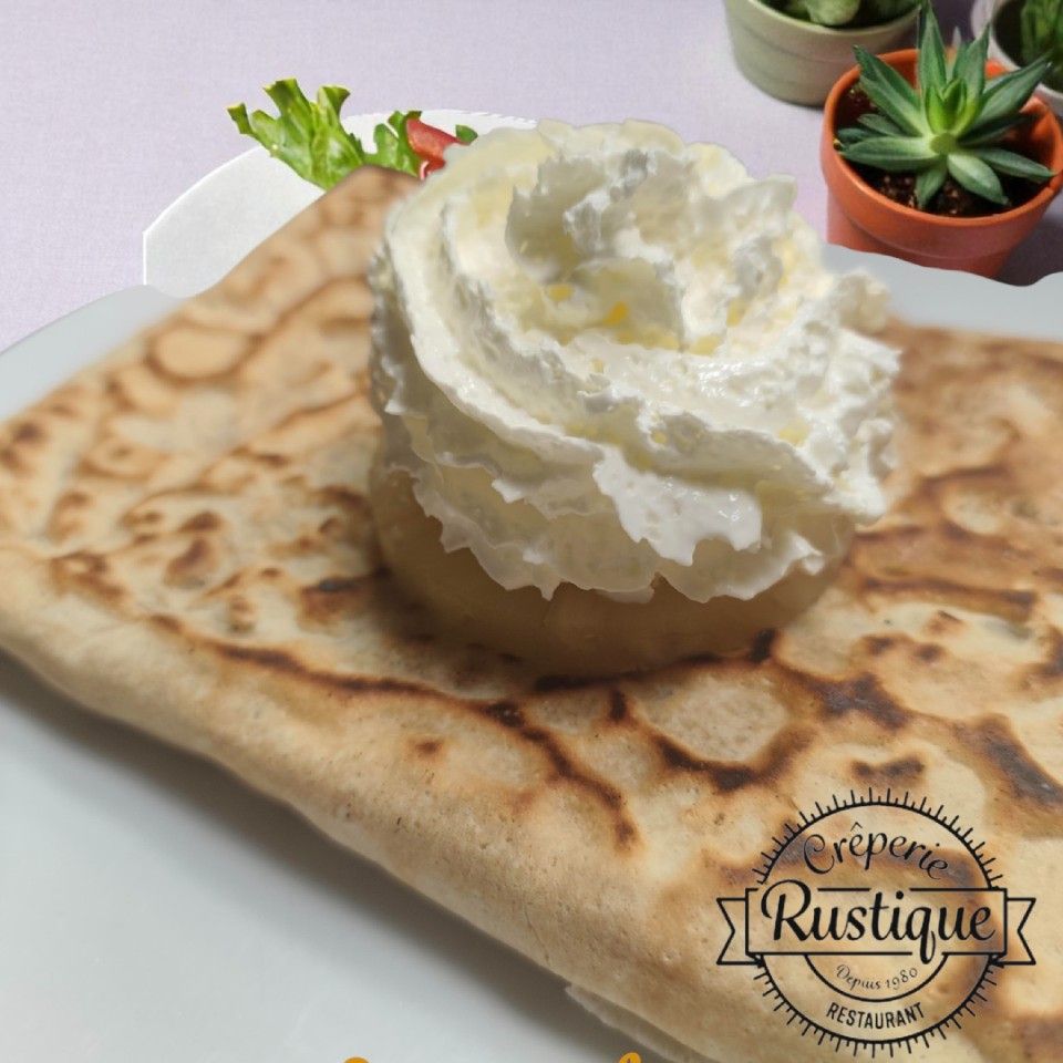 Crêpe à la crème fouettée, servie sur une assiette blanche avec de la laitue et de petites plantes grasses en arrière-plan.