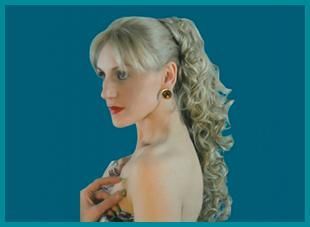 Una mujer con cabello largo y rubio lleva una cola de caballo y pendientes.