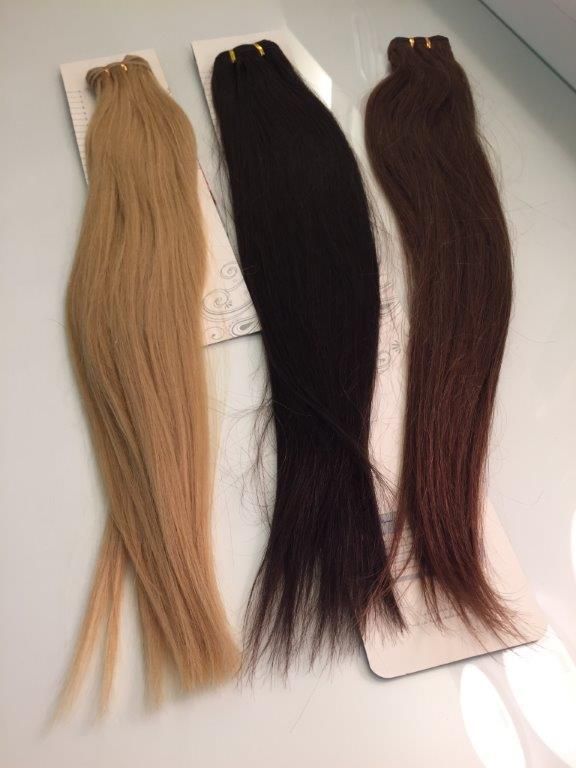 Tres extensiones de cabello de diferentes colores están sobre una mesa.
