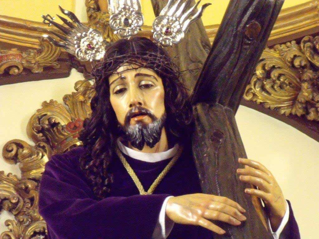 Una estatua de Jesús llevando una cruz con una corona de espinas en la cabeza.