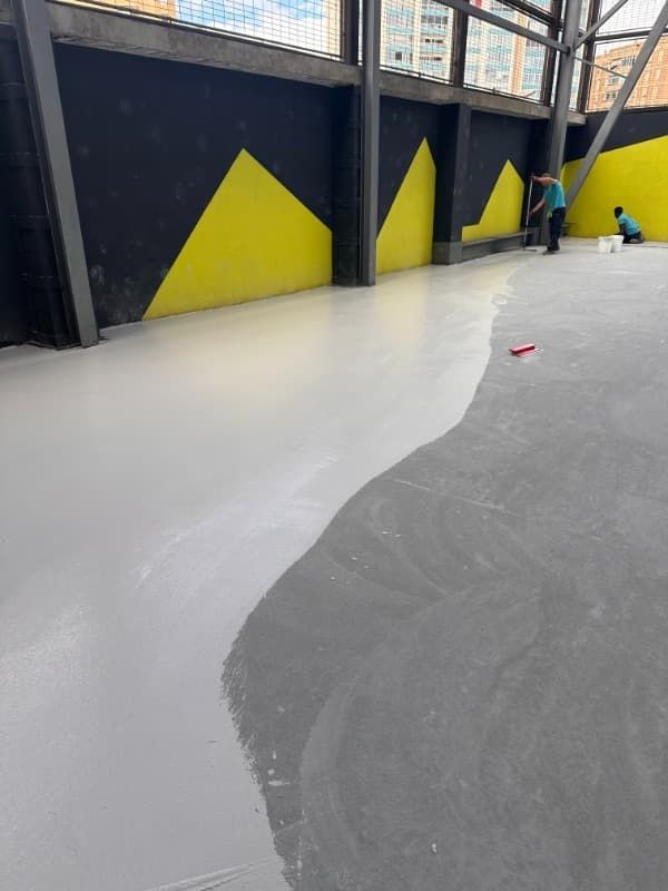 Skatepark cubierto con una rampa blanca curva sobre suelo gris y paredes negras con detalles triangulares amarillos.