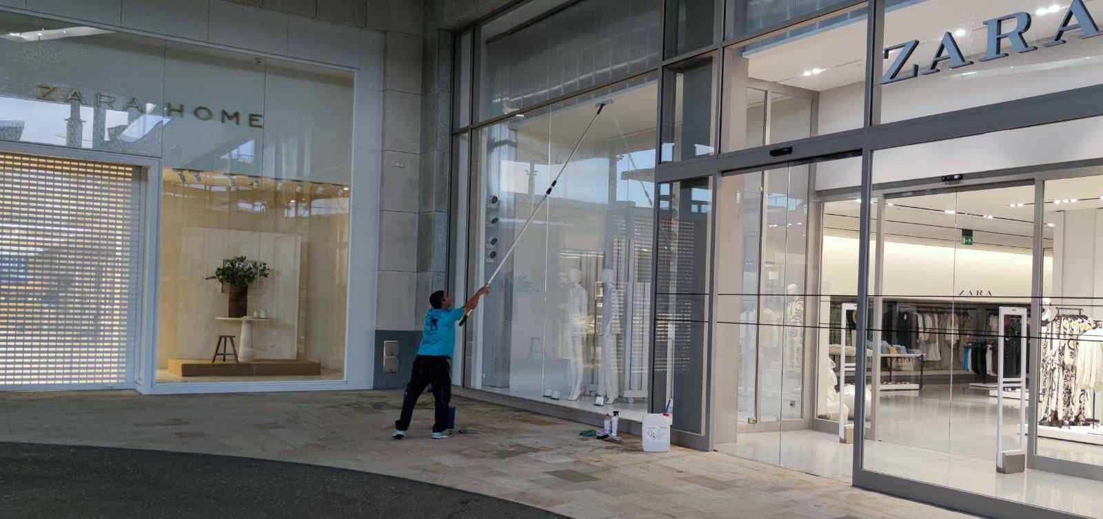 Un hombre está limpiando las ventanas de una tienda.