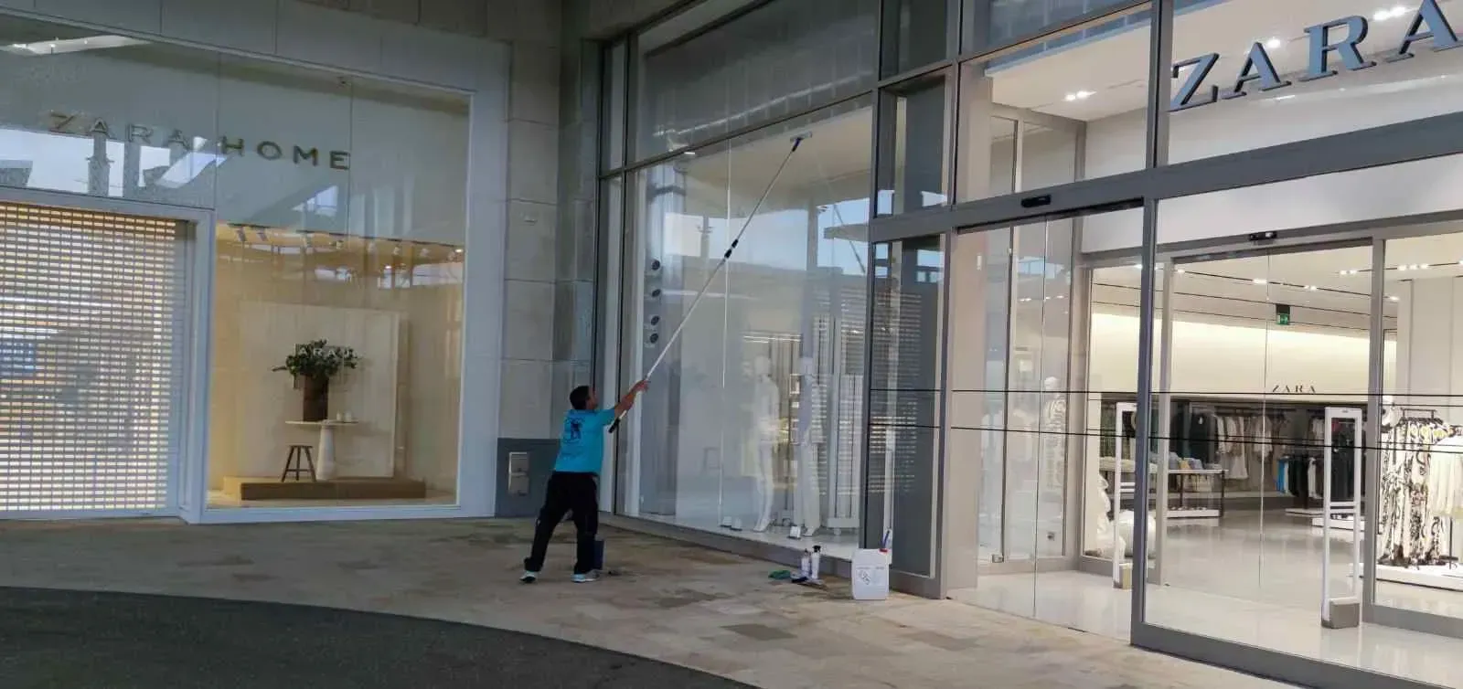 Una persona lava el exterior de cristal de una tienda de Zara.