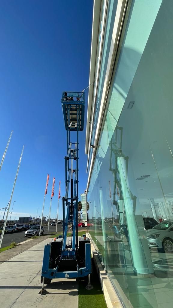 Un elevador aéreo azul está estacionado frente a un edificio.