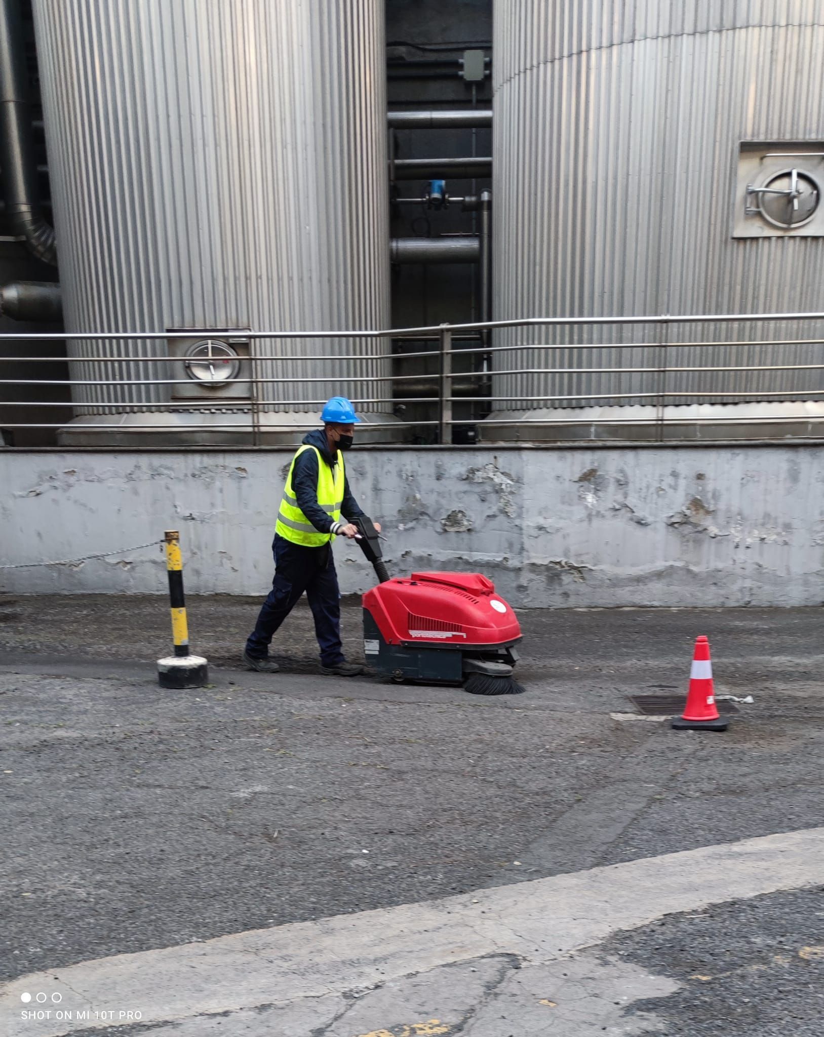 Un hombre está usando una máquina roja para limpiar un estacionamiento.
