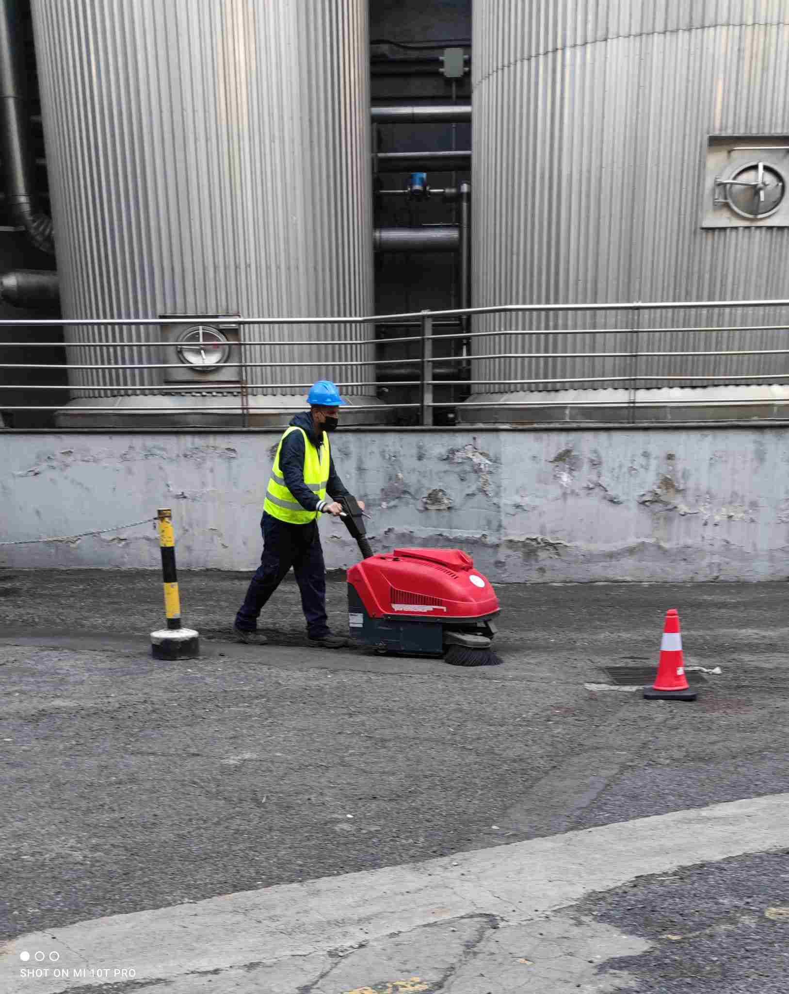 Un hombre está usando una máquina para limpiar el suelo en un estacionamiento.