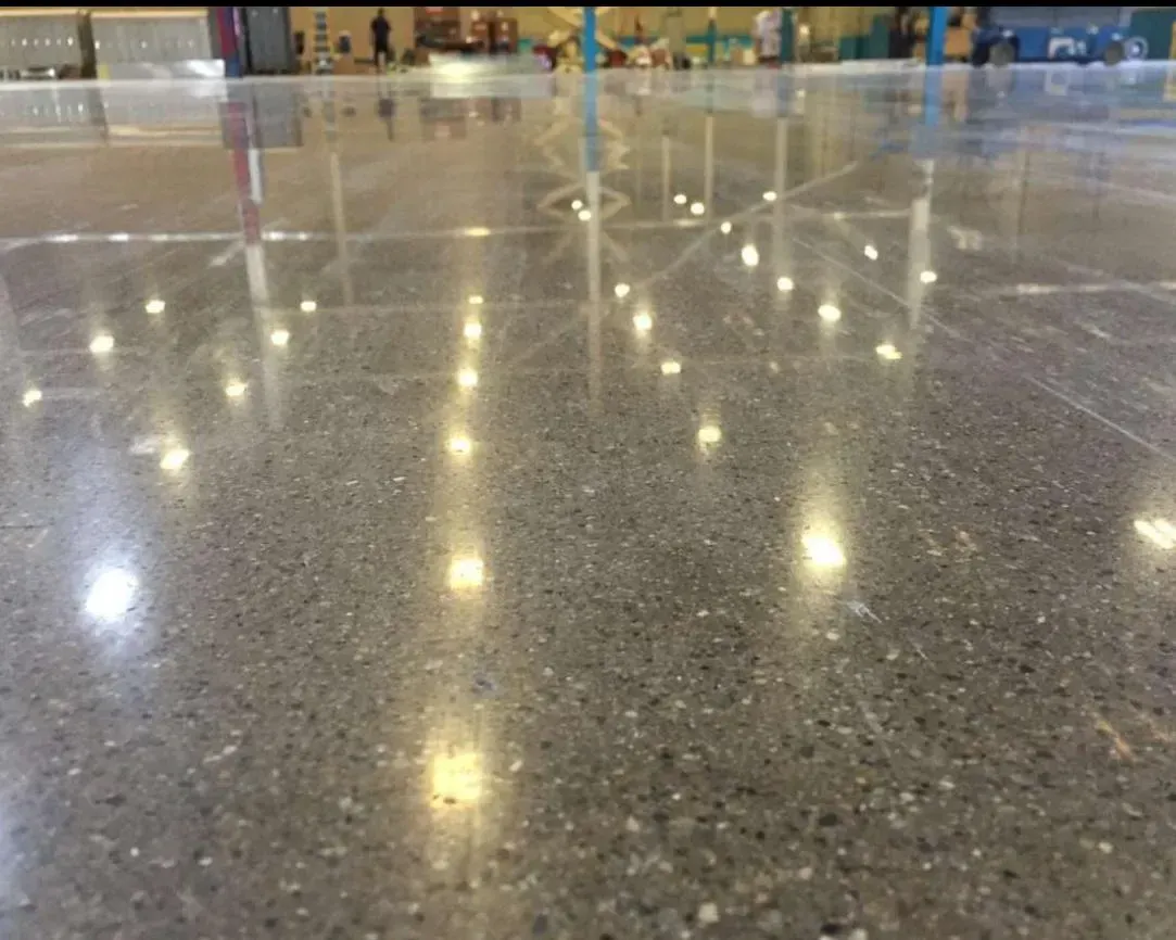 Un primer plano de un piso de hormigón brillante con luces reflejadas en él.