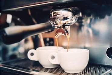 Zwei Tassen werden von einer Kaffeemaschine befüllt