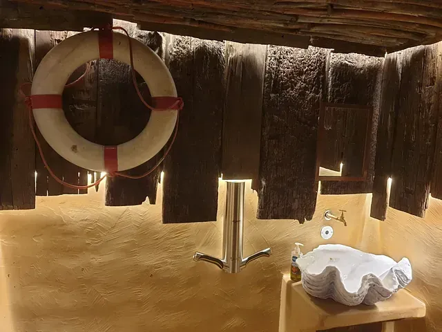 Baño con salvavidas, lavabo en forma de concha y vigas de madera.