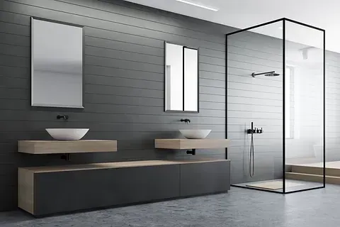 Baño moderno con paredes grises, ducha de cristal, dos lavabos y un tocador largo.