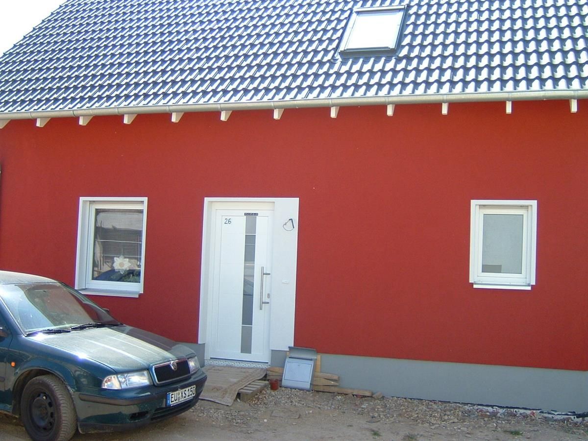 Ein Auto steht vor einem roten Haus