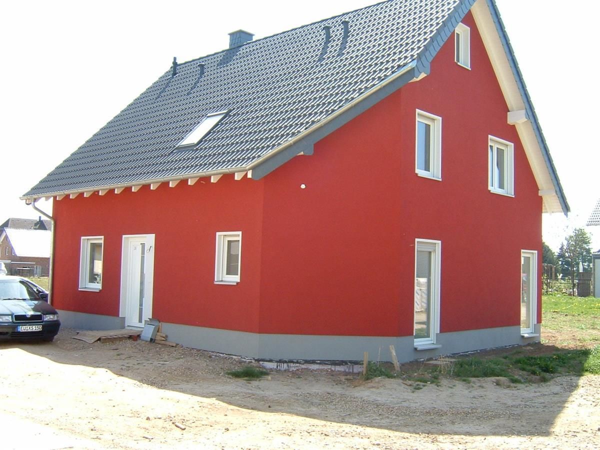 Ein rotes Haus mit einem davor geparkten Auto