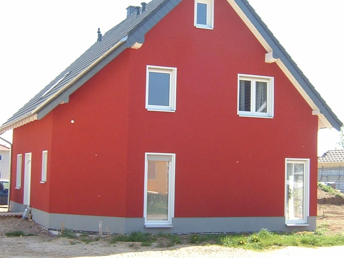Ein rotes Haus mit schwarzem Dach und weißen Fenstern