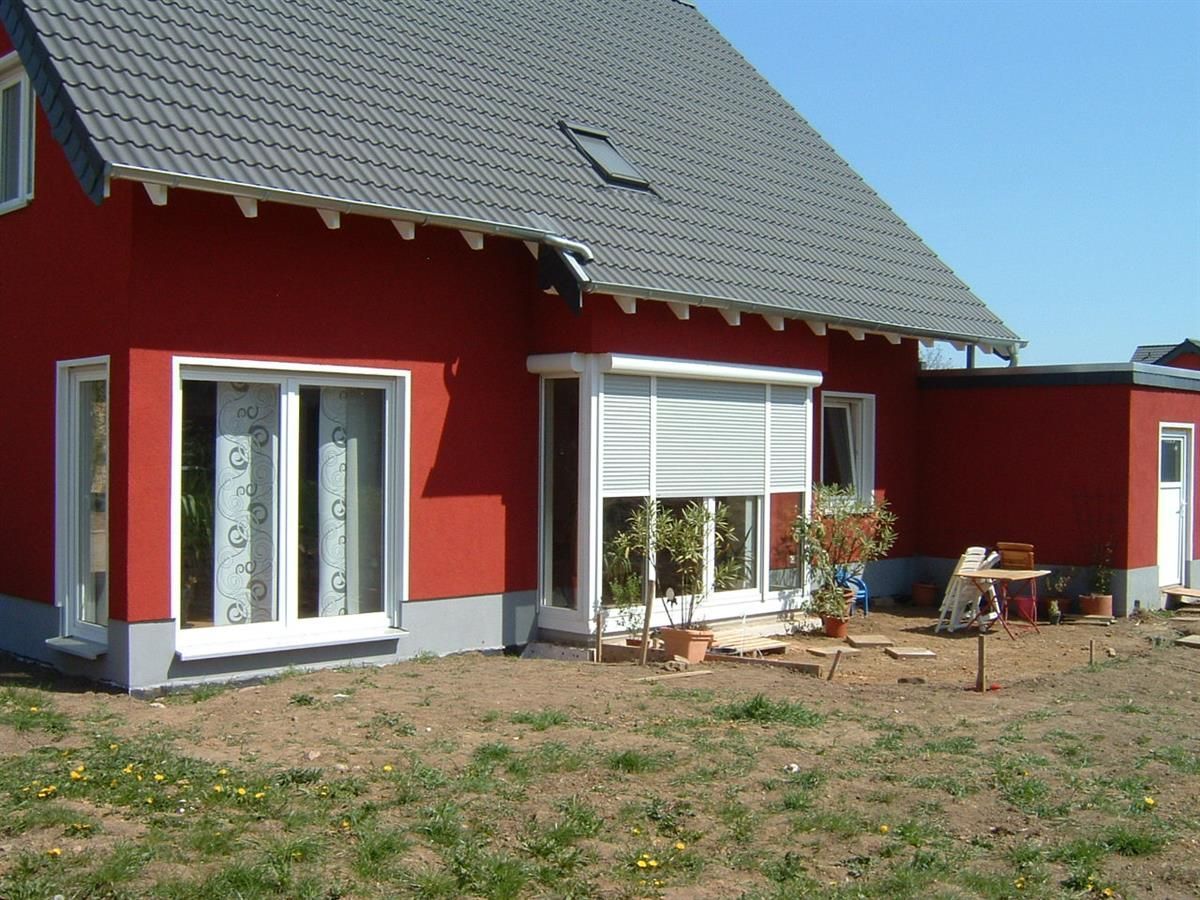 Ein rotes Haus mit grauem Dach und weißen Fenstern