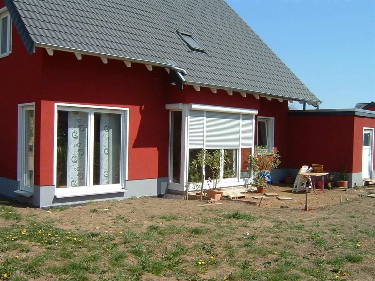 Ein rotes Haus mit grauem Dach und weißen Fenstern