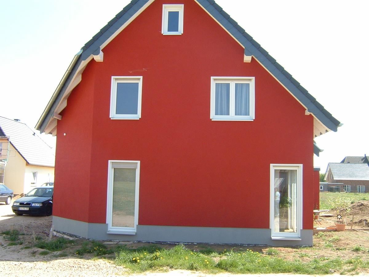 Ein rotes Haus mit schwarzem Dach und weißen Fenstern