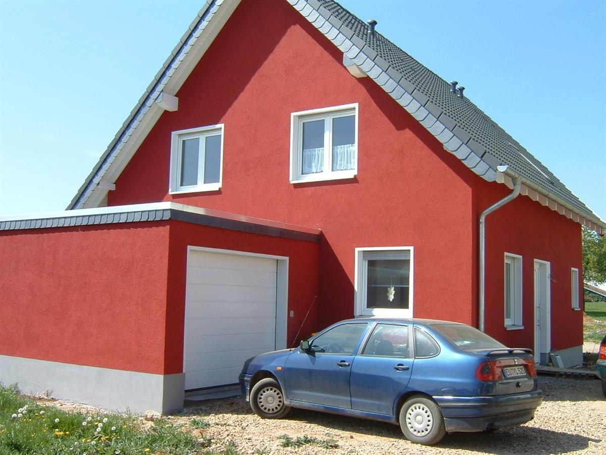 Ein blaues Auto steht vor einem roten Haus